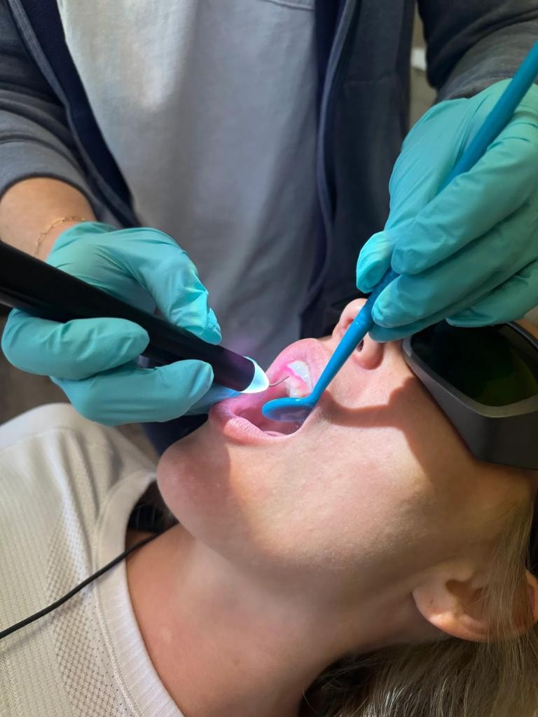 Dental hygienist using a diode laser for periodontal therapy during certification training